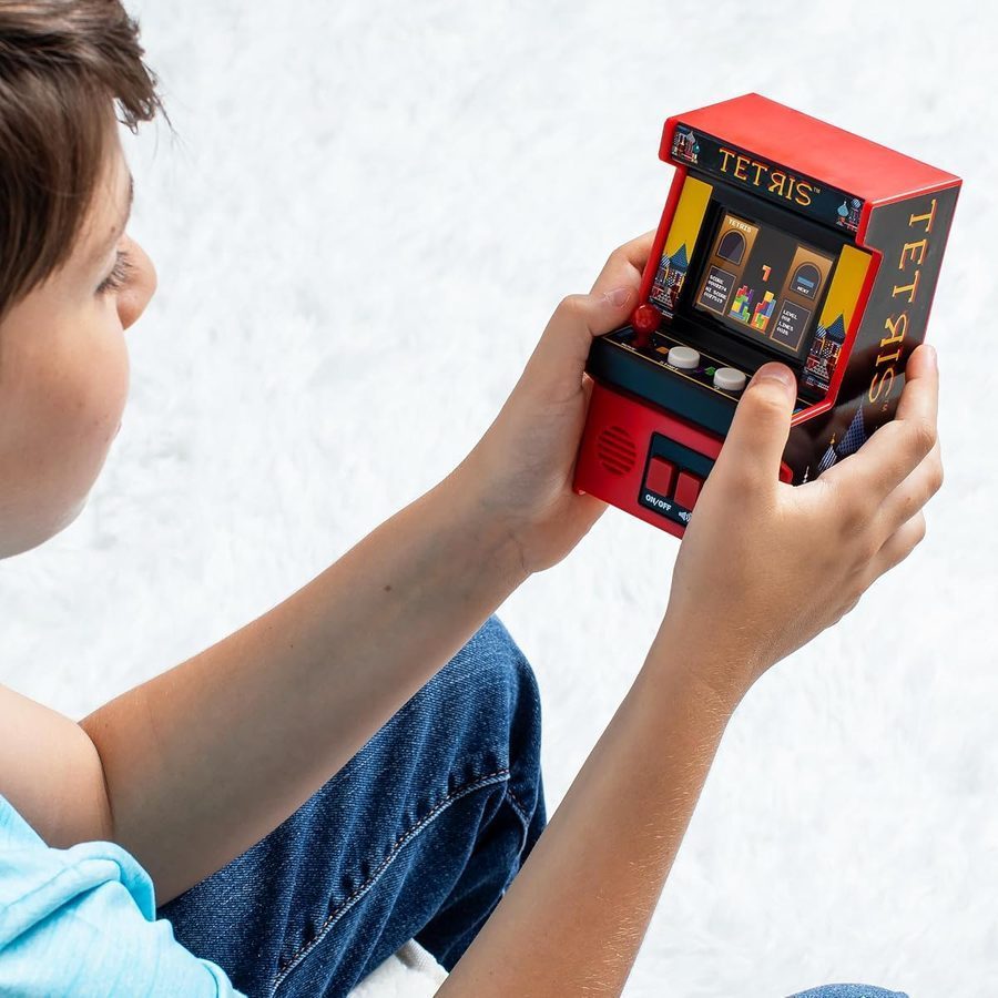 A boy holding an Arcade Classics Tetris handheld mini arcade cabinet